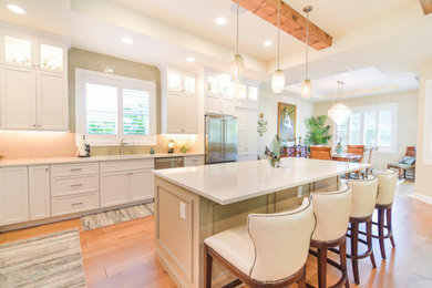 Kitchen - mid-sized coastal medium tone wood floor and beige floor kitchen idea in Tampa with an undermount sink, shaker cabinets, light wood cabinets, quartz countertops, multicolored backsplash, glass tile backsplash, stainless steel appliances, an island and white countertops