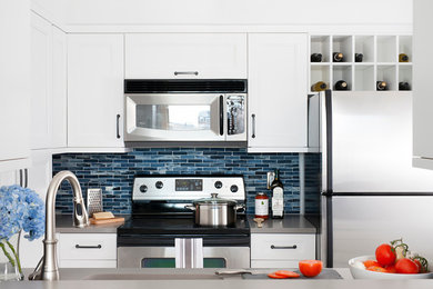 Inspiration for a small contemporary u-shaped enclosed kitchen remodel in DC Metro with an undermount sink, shaker cabinets, white cabinets, quartz countertops, blue backsplash, glass tile backsplash, stainless steel appliances and no island