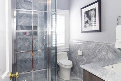 Inspiration for a mid-sized transitional 3/4 gray tile and marble tile marble floor and gray floor corner shower remodel in New York with flat-panel cabinets, dark wood cabinets, a one-piece toilet, gray walls, an undermount sink, marble countertops and a hinged shower door