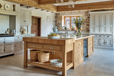 This is an example of a large farmhouse u-shaped kitchen/diner in West Midlands with a belfast sink, shaker cabinets, beige cabinets, quartz worktops, white splashback, engineered quartz splashback, stainless steel appliances, an island, beige floors, white worktops and a chimney breast.