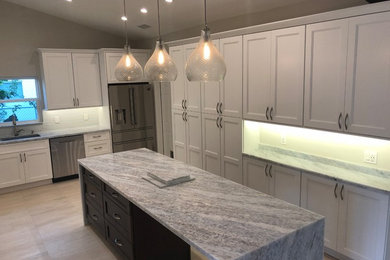 Design ideas for a mid-sized transitional u-shaped kitchen in Miami with an undermount sink, recessed-panel cabinets, white cabinets, grey splashback, glass tile splashback, stainless steel appliances, with island, beige floor and grey benchtop.