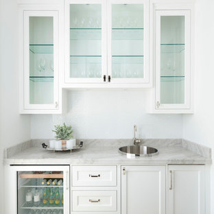 Einzeilige Mediterrane Hausbar mit hellem Holzboden, Bartresen, Einbauwaschbecken, Glasfronten, weißen Schränken, beigem Boden und grauer Arbeitsplatte in Dallas