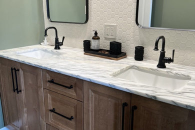 Mid-sized trendy master beige tile and ceramic tile porcelain tile, black floor and double-sink bathroom photo in Chicago with recessed-panel cabinets, brown cabinets, a one-piece toilet, green walls, an undermount sink, marble countertops, a niche and a built-in vanity