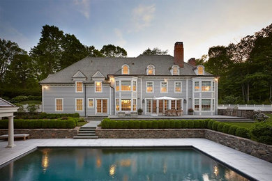 Large elegant gray three-story wood exterior home photo in Other with a hip roof