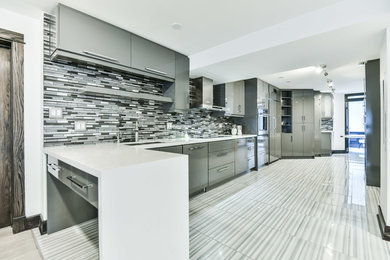 Large minimalist galley laminate floor and gray floor open concept kitchen photo in Toronto with an undermount sink, flat-panel cabinets, gray cabinets, solid surface countertops, multicolored backsplash, matchstick tile backsplash, stainless steel appliances, a peninsula and white countertops