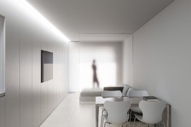 Imagen de salón abierto y beige y blanco minimalista pequeño sin chimenea con paredes blancas, suelo de piedra caliza, televisor colgado en la pared y suelo beige