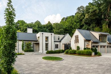 Ejemplo de fachada de casa beige y negra tradicional renovada grande de dos plantas con revestimiento de estuco y tejado de metal