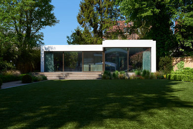 Small contemporary one-storey white exterior in London with mixed siding, a flat roof and a green roof.