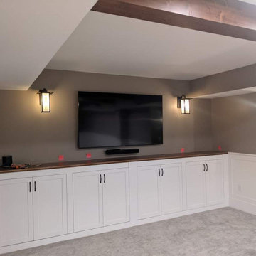 Basement with a banquette, beams, wainscot and bookcases