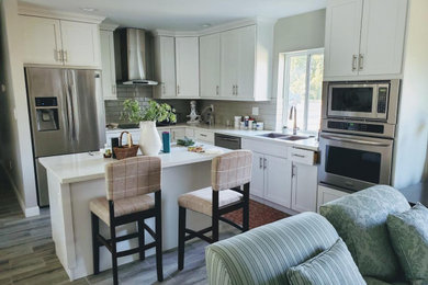 Mid-sized transitional l-shaped vinyl floor, gray floor and vaulted ceiling kitchen pantry photo in Phoenix with a double-bowl sink, shaker cabinets, white cabinets, quartzite countertops, white backsplash, subway tile backsplash, stainless steel appliances, an island and white countertops
