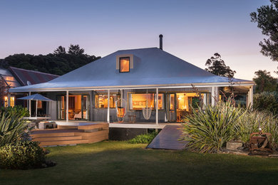 Small beach style two-storey black exterior in Auckland with wood siding and a hip roof.