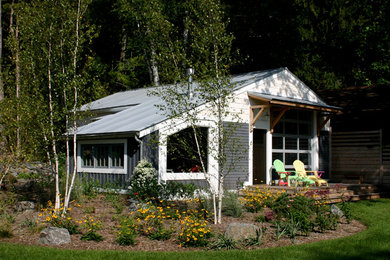 This is an example of a small beach style one-storey grey house exterior in Milwaukee with wood siding, a gable roof and a metal roof.