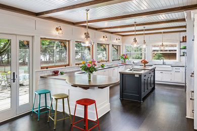 Beach style u-shaped dark wood floor kitchen photo in Milwaukee with a farmhouse sink, shaker cabinets, white cabinets, white backsplash, subway tile backsplash and an island