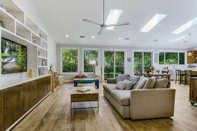 Photo of a mid-sized modern open concept family room in Austin with grey walls, medium hardwood floors, a built-in media wall and brown floor.