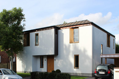 Imagen de fachada de casa blanca y marrón grande de dos plantas con ladrillo pintado, tejado a doble faldón y tejado de metal