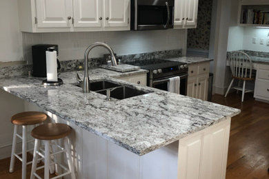 Example of a mid-sized classic l-shaped dark wood floor and brown floor enclosed kitchen design in Richmond with a double-bowl sink, raised-panel cabinets, white cabinets, granite countertops, white backsplash, porcelain backsplash, a peninsula and gray countertops