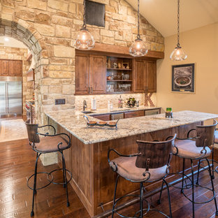 This is an example of a mediterranean u-shaped wet bar in Austin with a submerged sink, raised-panel cabinets, dark wood cabinets, beige splashback and dark hardwood flooring.