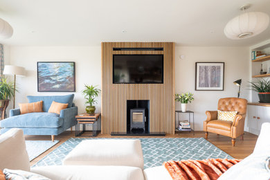 This is an example of a contemporary living room in Cambridgeshire with a wood burning stove, a built-in media unit and panelled walls.
