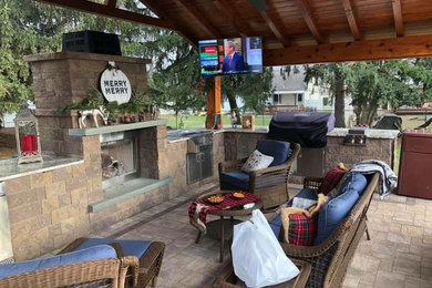 Photo of a small backyard patio in New York with with fireplace, brick pavers and a gazebo/cabana.