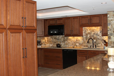 Photo of a mid-sized arts and crafts u-shaped eat-in kitchen in Orlando with a peninsula, an undermount sink, recessed-panel cabinets, medium wood cabinets, granite benchtops, multi-coloured splashback, stone tile splashback, black appliances and ceramic floors.