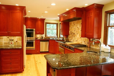 Example of a classic u-shaped light wood floor enclosed kitchen design in Portland with a single-bowl sink, dark wood cabinets, granite countertops, beige backsplash, stainless steel appliances and a peninsula