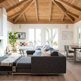Example of a huge beach style open concept light wood floor and brown floor living room design in Los Angeles with white walls and a standard fireplace