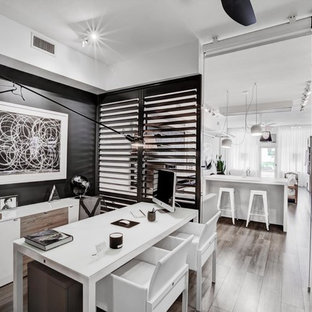 Inspiration för ett funkis hemmabibliotek, med svarta väggar, mellanmörkt trägolv och ett fristående skrivbord