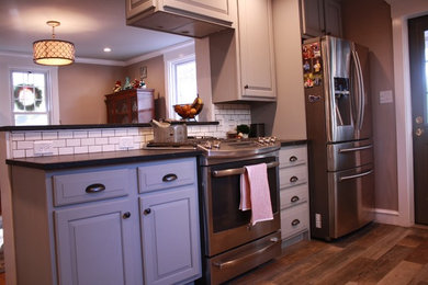 Mid-sized elegant galley porcelain tile eat-in kitchen photo in Philadelphia with a farmhouse sink, raised-panel cabinets, gray cabinets, soapstone countertops, white backsplash, ceramic backsplash and stainless steel appliances