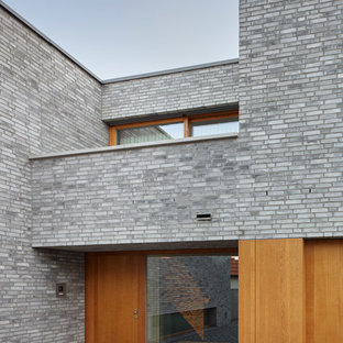 Выдающиеся фото от архитекторов и дизайнеров интерьера: входная дверь среднего размера в стиле модернизм с серыми стенами, гранитным полом, одностворчатой входной дверью, входной дверью из дерева среднего тона и серым полом