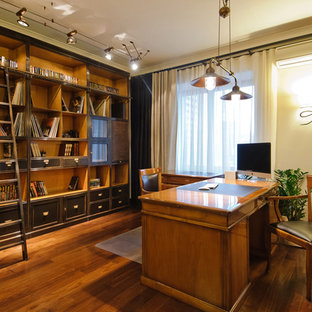 На фото: рабочее место в классическом стиле с отдельно стоящим рабочим столом, белыми стенами и паркетным полом среднего тона с