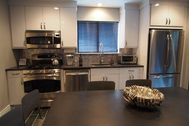 Inspiration for a contemporary galley slate floor eat-in kitchen remodel in New York with an undermount sink, flat-panel cabinets, white cabinets, granite countertops, metallic backsplash, metal backsplash and stainless steel appliances