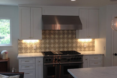Example of a large trendy l-shaped dark wood floor open concept kitchen design in San Francisco with a farmhouse sink, shaker cabinets, white cabinets, marble countertops, terra-cotta backsplash, stainless steel appliances and an island