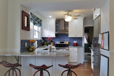 Mid-sized trendy u-shaped light wood floor and brown floor kitchen photo in New York with an undermount sink, shaker cabinets, white cabinets, granite countertops, blue backsplash, stainless steel appliances and a peninsula