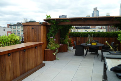 Large trendy concrete paver patio container garden photo in New York with a pergola