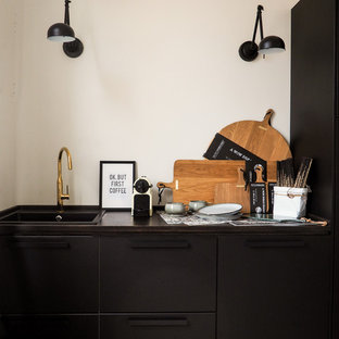 Создайте стильный интерьер: маленькая отдельная, линейная кухня в скандинавском стиле с накладной раковиной, плоскими фасадами, черными фасадами, столешницей из дерева, белым фартуком, полом из цементной плитки, красным полом и коричневой столешницей без острова - последний тренд