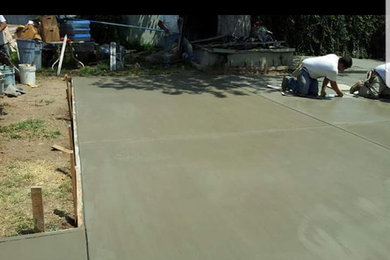 This is an example of a large back driveway full sun garden in Los Angeles with a garden path and concrete paving.