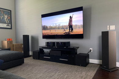 Imagen de cine en casa cerrado minimalista pequeño con paredes grises y televisor colgado en la pared