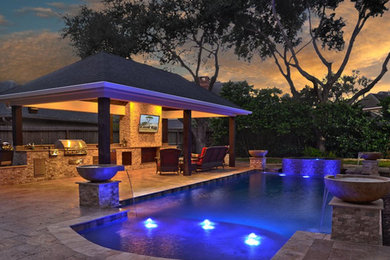 This is an example of a large contemporary backyard custom-shaped natural pool in Houston with a water feature and natural stone pavers.
