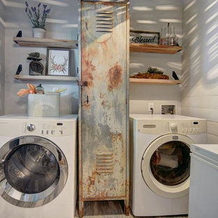 オースティンの小さいカントリー風おしゃれな洗濯室 (ヴィンテージ仕上げキャビネット、グレーの壁、無垢フローリング、左右配置の洗濯機・乾燥機、グレーの床) の写真