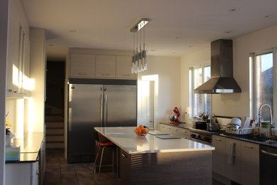 Example of a large trendy u-shaped enclosed kitchen design in Montreal with an undermount sink, flat-panel cabinets, white cabinets, quartz countertops, stainless steel appliances and an island