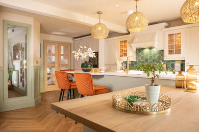 Example of a large transitional single-wall brown floor and light wood floor eat-in kitchen design in Other with a single-bowl sink, shaker cabinets, green backsplash, ceramic backsplash, stainless steel appliances, an island, multicolored countertops, beige cabinets and quartzite countertops