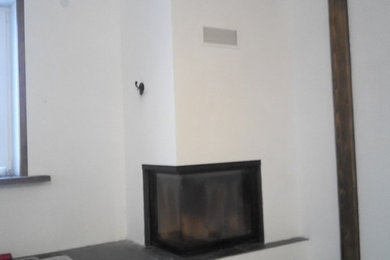 Cette image montre un petit salon minimaliste ouvert avec une salle de réception, un mur blanc, un sol en carrelage de porcelaine, une cheminée d'angle, un manteau de cheminée en plâtre et aucun téléviseur.