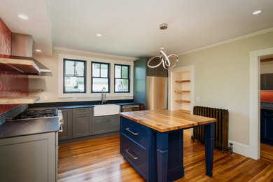 Example of a mountain style l-shaped medium tone wood floor kitchen design in Portland Maine with shaker cabinets and an island