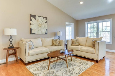 This is an example of a mid-sized transitional open concept living room in Boston with beige walls, medium hardwood floors, a standard fireplace, a stone fireplace surround and no tv.