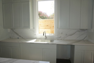 Inspiration for a craftsman kitchen remodel in Houston with a single-bowl sink, white backsplash, stone slab backsplash, stainless steel appliances and an island