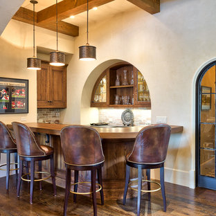 他の地域の中サイズの地中海スタイルのおしゃれな着席型バー (アンダーカウンターシンク、レイズドパネル扉のキャビネット、濃色木目調キャビネット、木材カウンター、赤いキッチンパネル、レンガのキッチンパネル、濃色無垢フローリング、茶色いキッチンカウンター) の写真