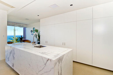 Photo of a mid-sized contemporary single-wall eat-in kitchen in Sydney with flat-panel cabinets, white cabinets, stainless steel appliances, with island, beige floor, white benchtop, an undermount sink and marble benchtops.