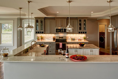 Open concept kitchen - large transitional u-shaped medium tone wood floor and brown floor open concept kitchen idea in Other with a farmhouse sink, recessed-panel cabinets, gray cabinets, quartz countertops, gray backsplash, stone tile backsplash, stainless steel appliances and two islands