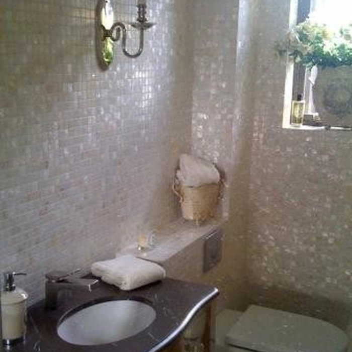 White mother of pearl mosaics in a bathroom area with stone basin