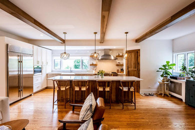 Inspiration for a large rustic l-shaped medium tone wood floor, brown floor and exposed beam open concept kitchen remodel in Chicago with a farmhouse sink, shaker cabinets, medium tone wood cabinets, quartzite countertops, blue backsplash, ceramic backsplash, stainless steel appliances, an island and white countertops